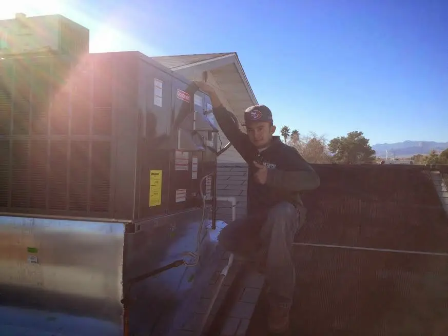 HVAC technician performing AC Tune-Up on a rooftop unit in St. Simons